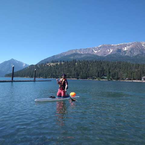 a man riding on the back of a boat next to a lake