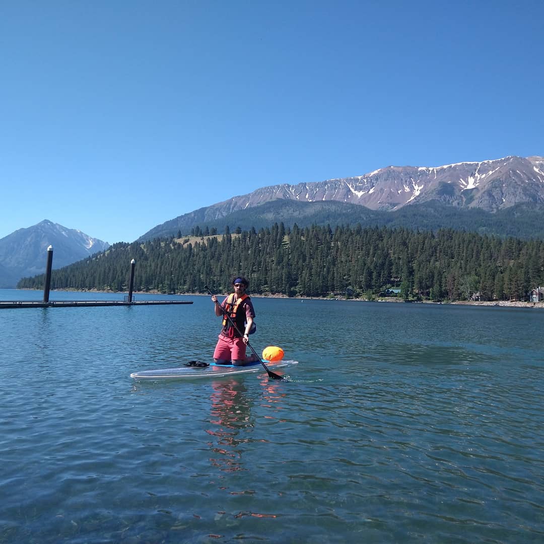 a man riding on the back of a boat next to a lake