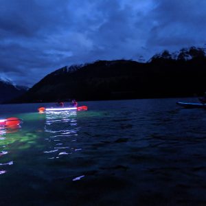 a small boat in a body of water with a mountain in the dark