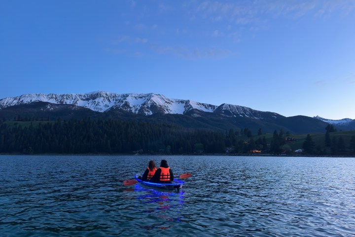 a single boat at dusk with a mountain in the background